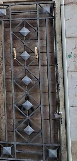Il cancello di ferro accanto all'ingresso, con la fila verticale di rombi in rilievo